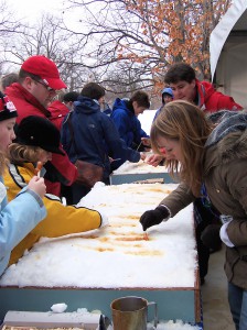 Guests making maple taffy outdoors at a long table