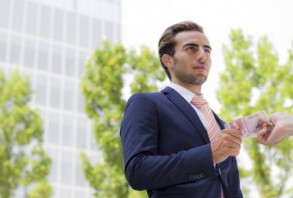 Young businessman outside office taking banknotes