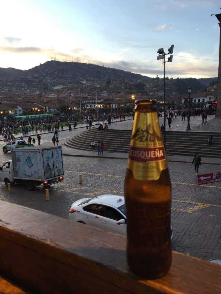 bottle of beer outside on railing overlooking mountains