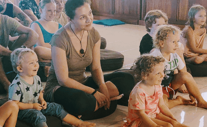 Women & children sitting on the floor listening to someone at the front of the room