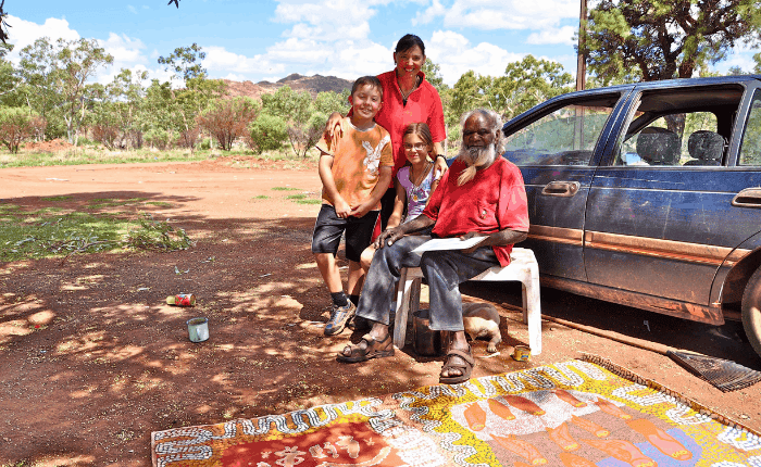 people standing & sitting beside a car