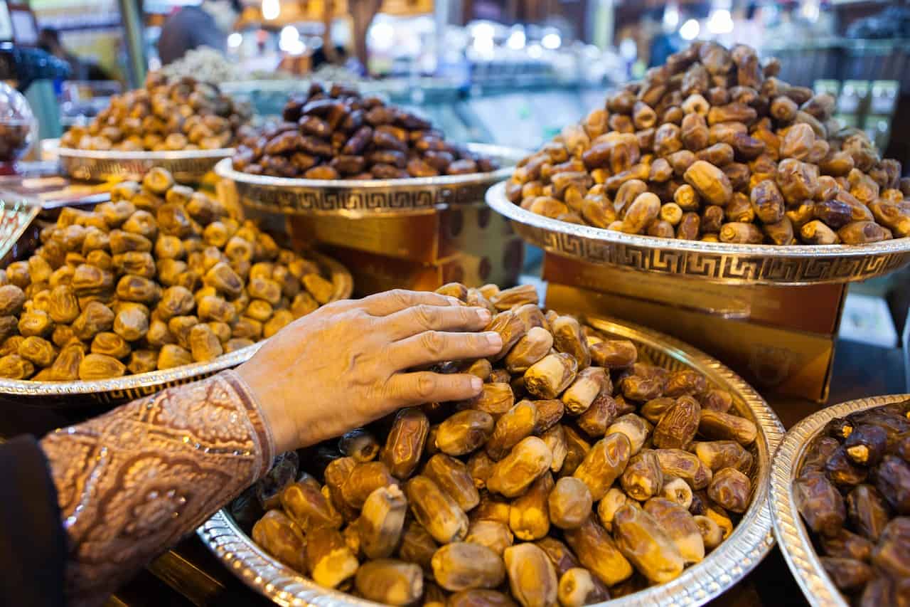 several plates of dates with woman's hand showing