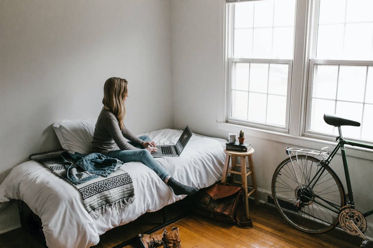 person sitting on the bed looking at a laptop