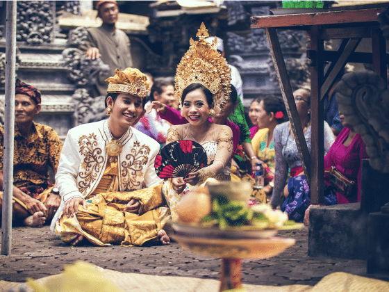 A traditional Thai wedding ceremony with elaborative clothing and a bowl of fruit