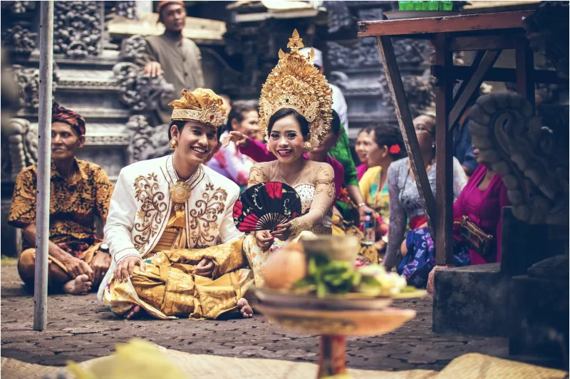 A traditional Thai wedding ceremony with elaborative clothing and a bowl of fruit