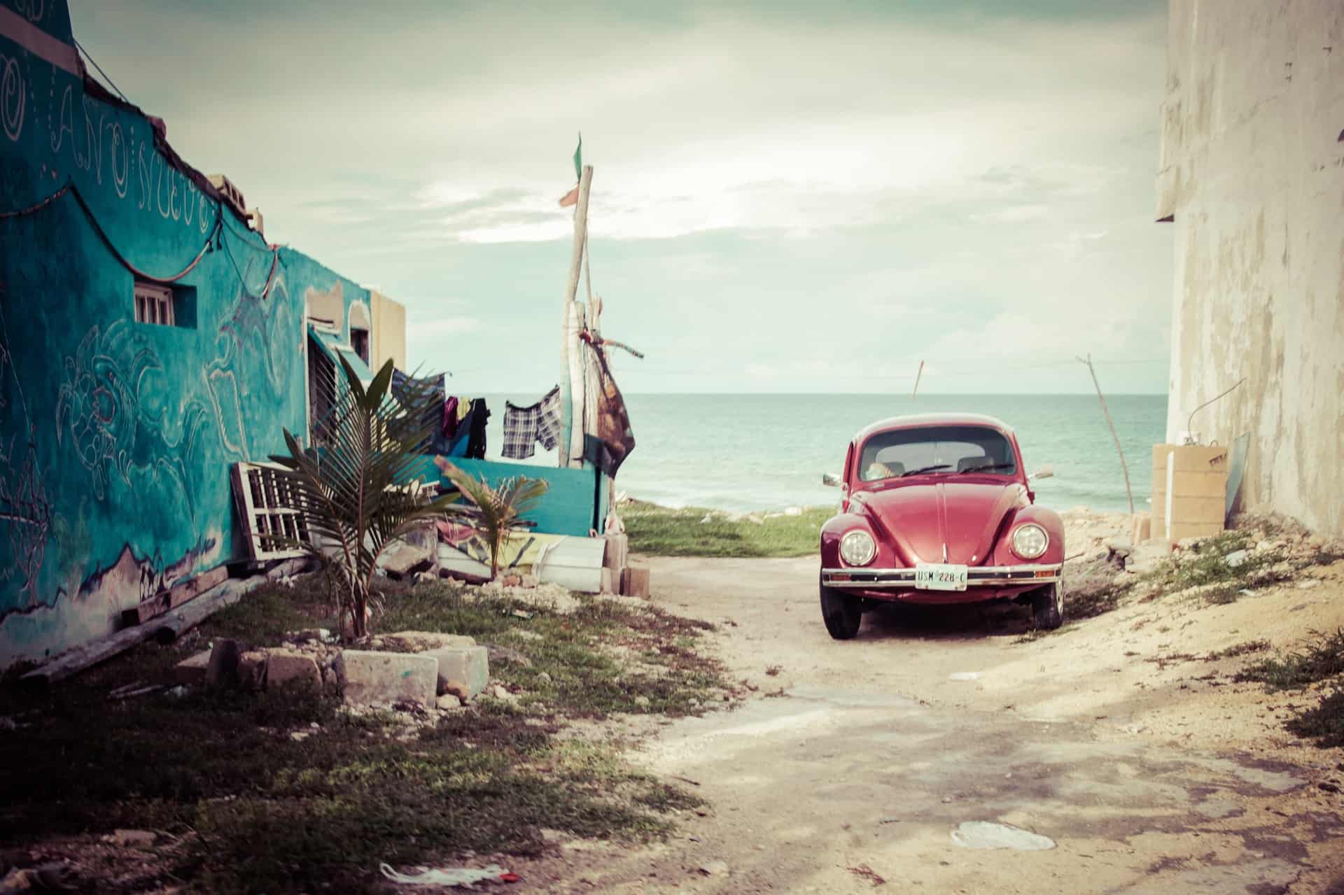 view of an old red car with the beautiful ocean behind