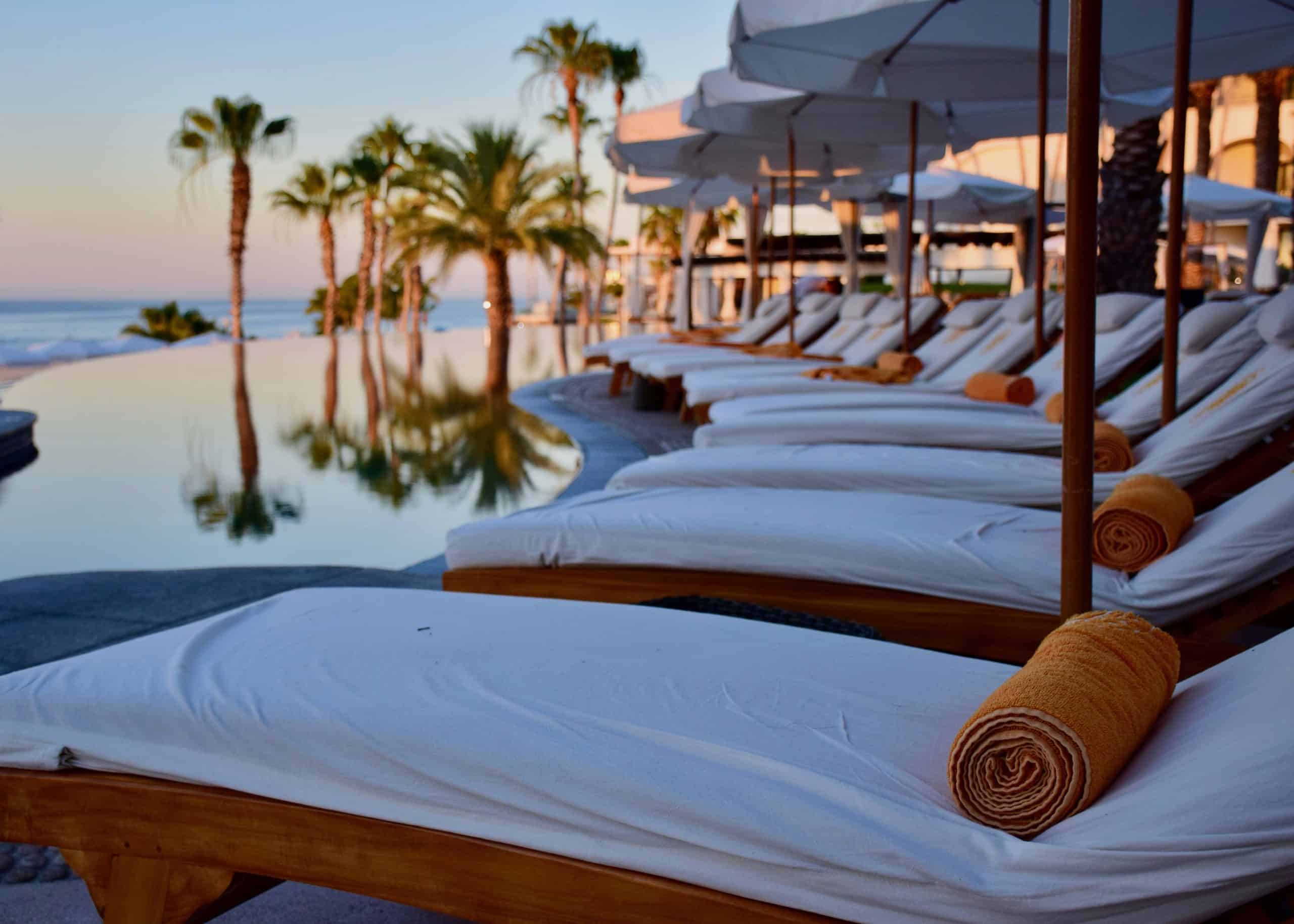 row of lounge chairs with palm trees in the distance