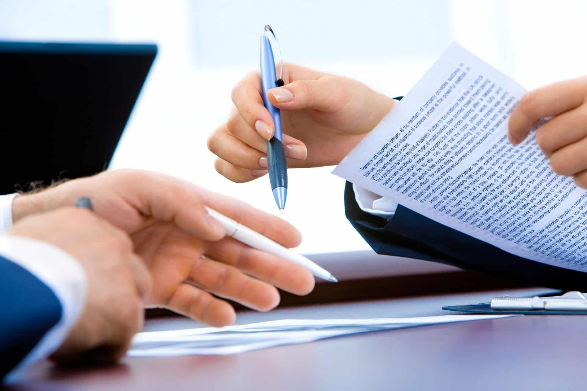 two people holding pens discussing a contract