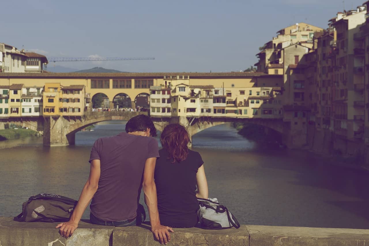 couple sitting on a wall dangling their feet over