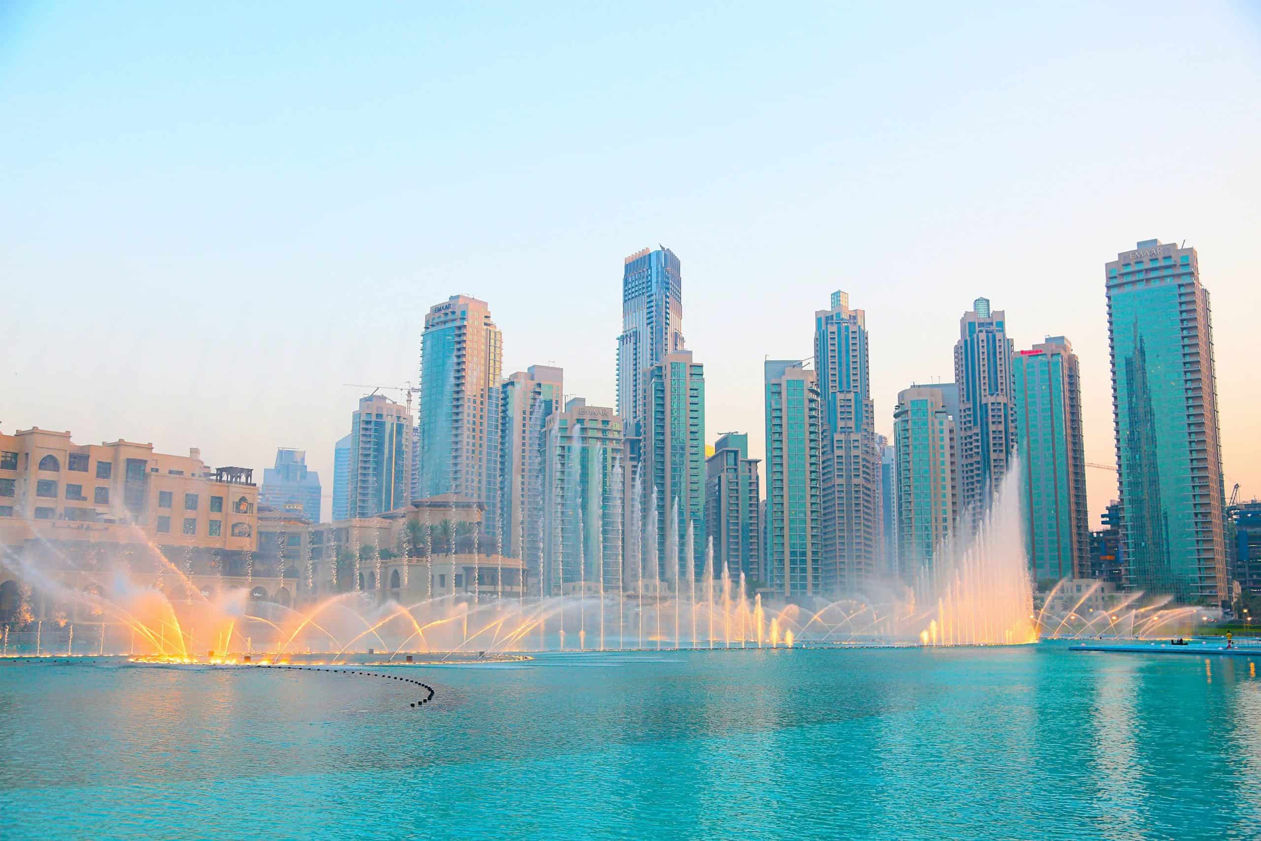 fountains in a beautiful pool with highrise buildings behind