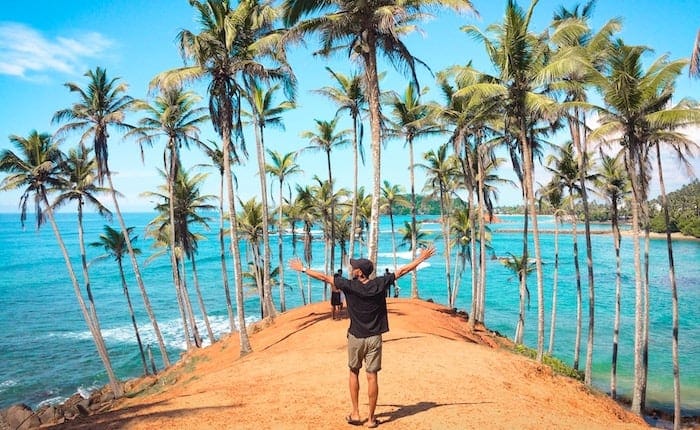 men arms open in island full of palms