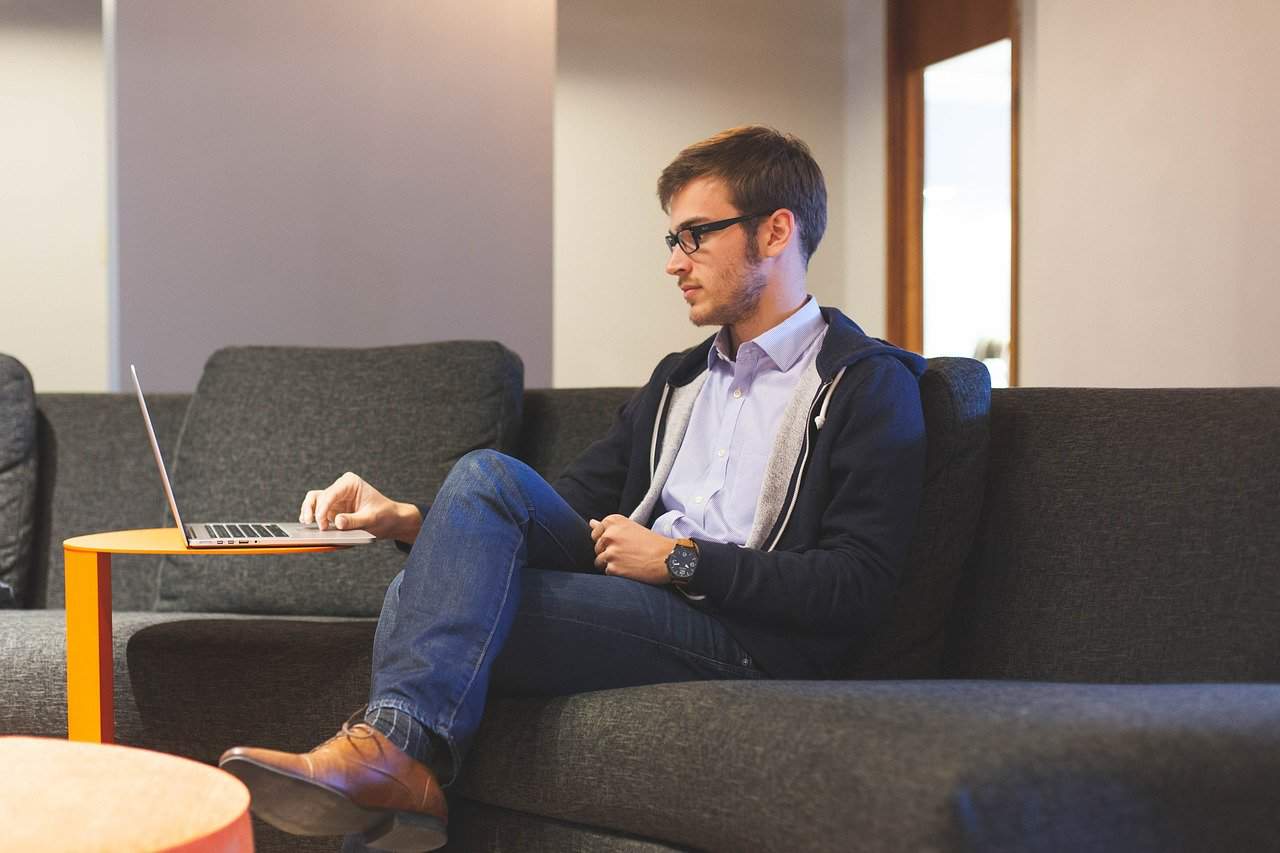 Entrepreneur filing his taxes on his laptop while he sits on a couch