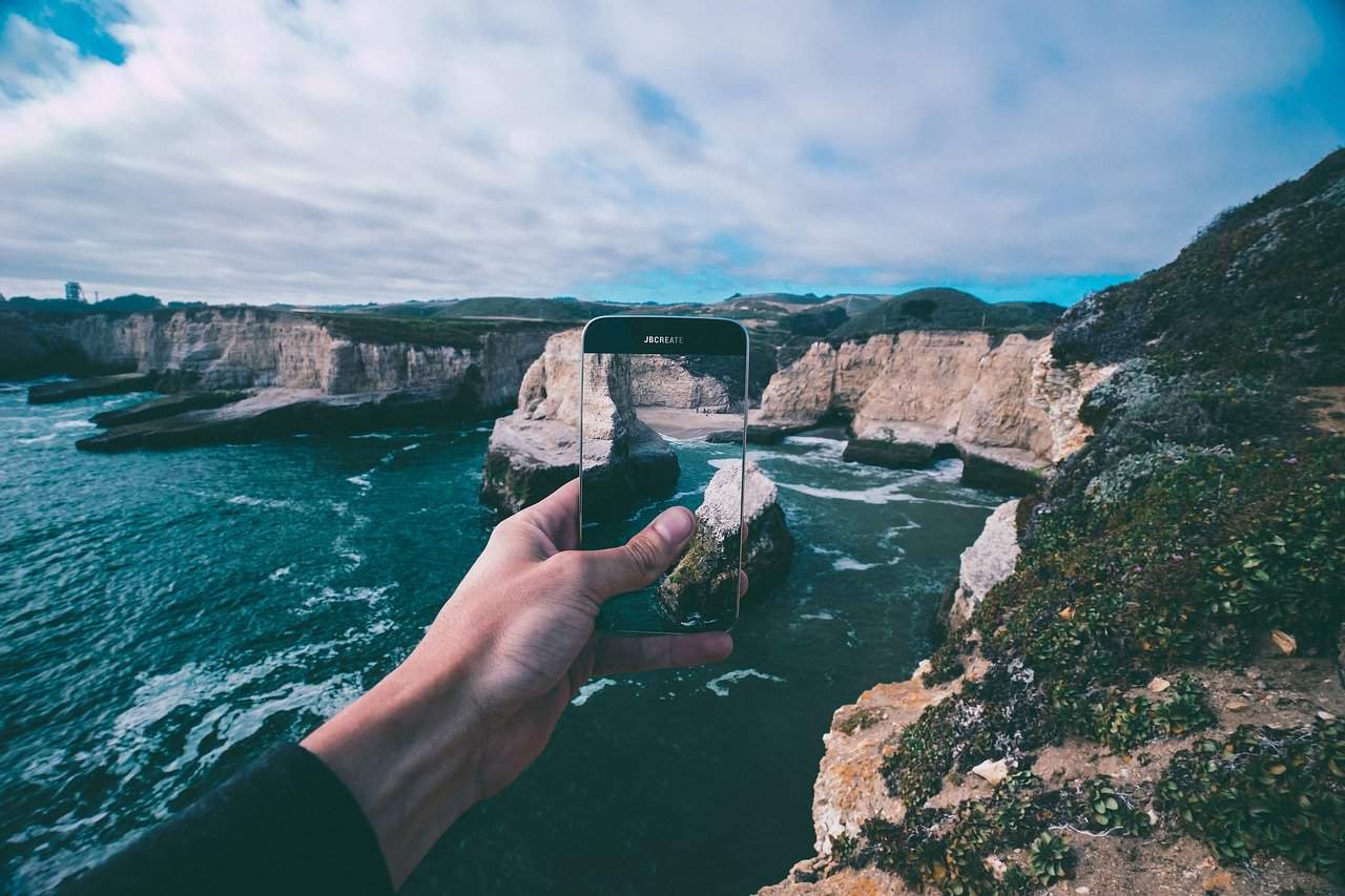 Hand with phone overlooking water