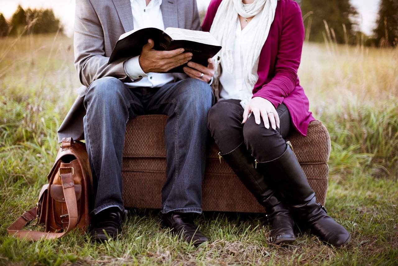 couple reading a book on a couch outside