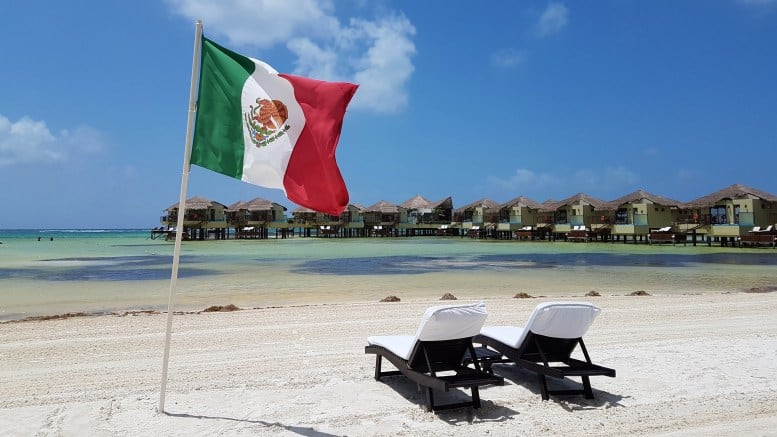 two lounge chairs on the beach with a Mexican Flag