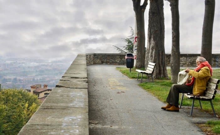 Male Senior sitting on a bench reading a newspaper