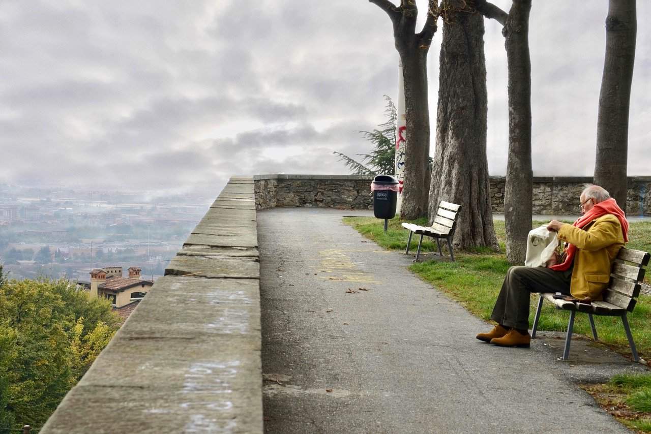 Male Senior sitting on a bench reading a newspaper