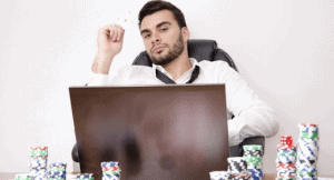 man in front of computer with poker chips around him