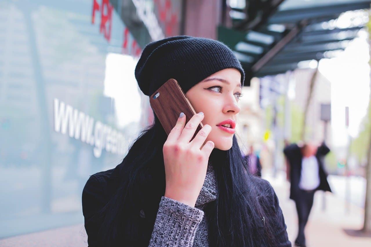 girl holding mobile phone with dark whool hat on