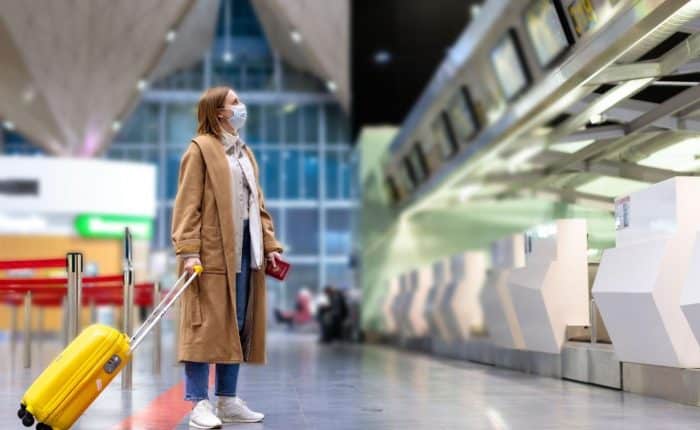 Girl with mask with suitcase in empty airport