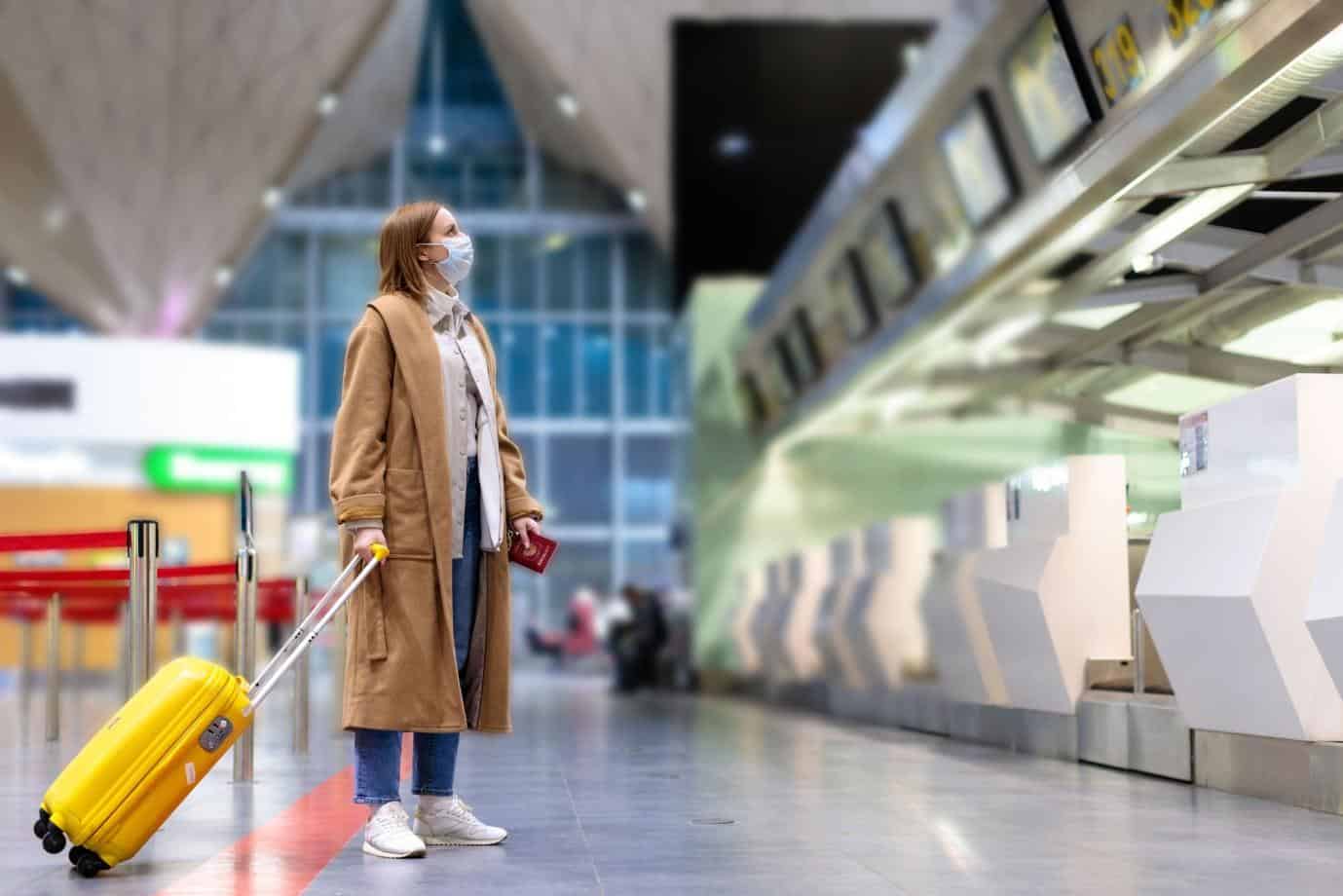 Girl with mask with suitcase in empty airport