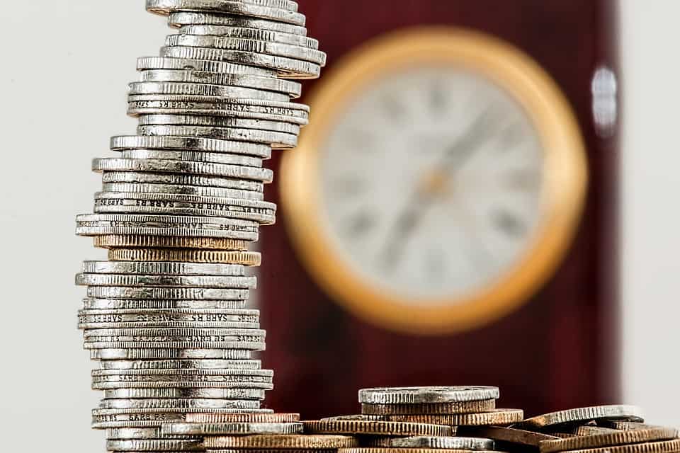 Coins in the forefront and a clock in the background