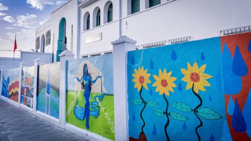 Various art adorns a street wall in Asilah, Morocco.
