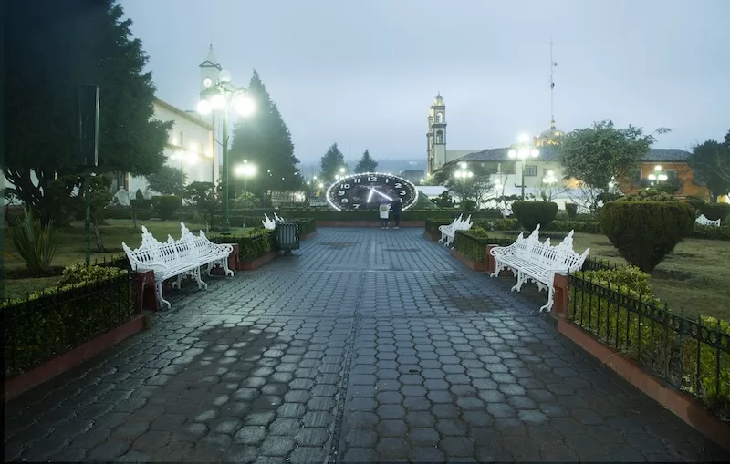 The iconic large flower clock shines through the misty main square of Zacatlan de las Manzanas, Puebla, Mexico.