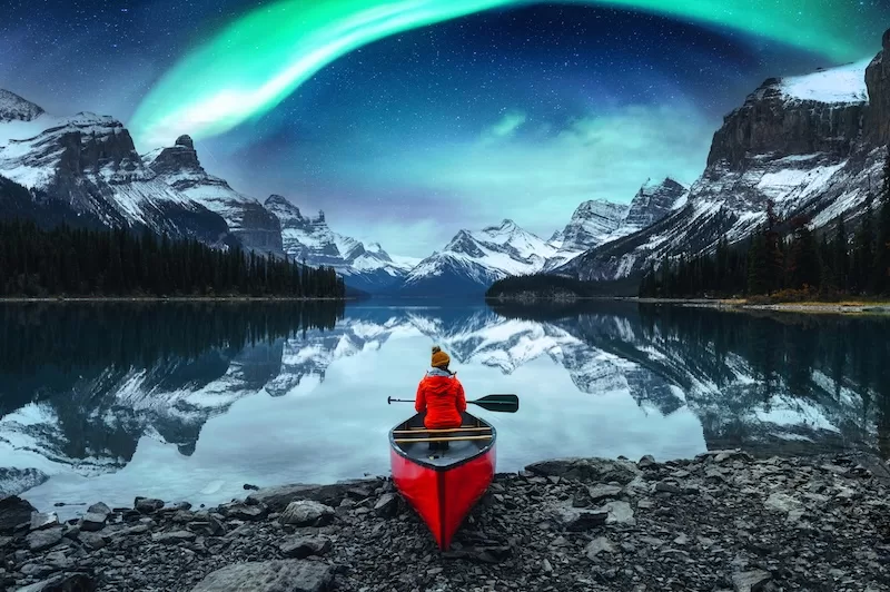 A woman takes in the aurora borealis over Spirit Island, Jasper National Park, Alberta, Canada