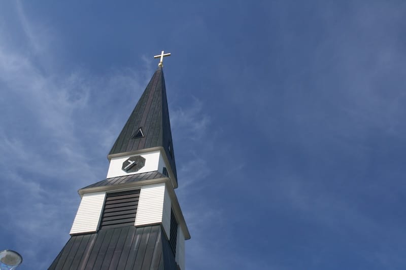 The spire of Rovaniemi Church rises against an unbroken blue sky