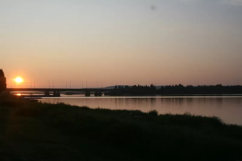 Near midnight, the sun hovers on the horizon above the Kemijoki River