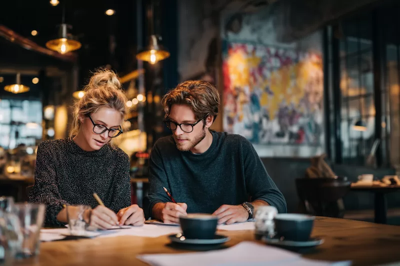  Expats reviewing their finances over coffee, weighing how taxes and daily costs can shape life in a new country.