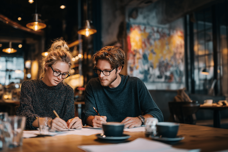 Expats reviewing their finances over coffee, weighing how taxes and daily costs can shape life in a new country.