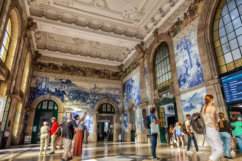 Even waiting for a train in Portugal feels cultural: tiled murals, sunlight, and energy of a big city with people traveling to and fro.