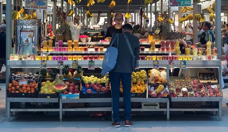 Fresh fruit, juices, and vibrant produce at Porto’s Bolhão market; local flavors that keep grocery costs low and quality high.