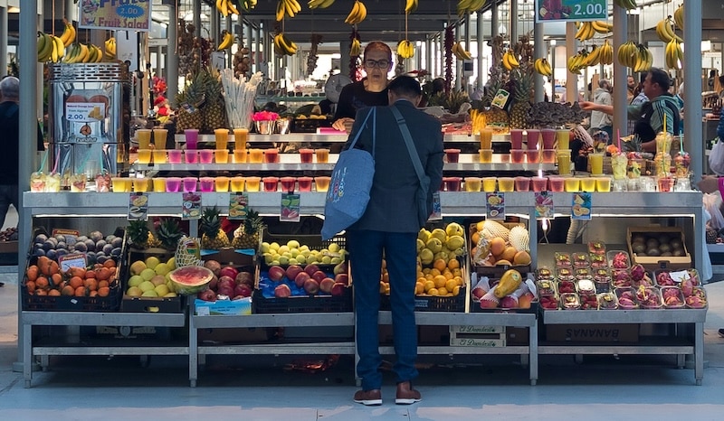 Fresh fruit, juices, and vibrant produce at Porto’s Bolhão market; local flavors that keep grocery costs low and quality high.