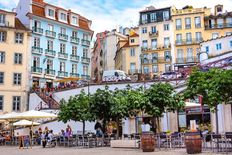 A Lisbon square alive with locals and expats, framed by the city’s trademark colorful façades and endless charm.