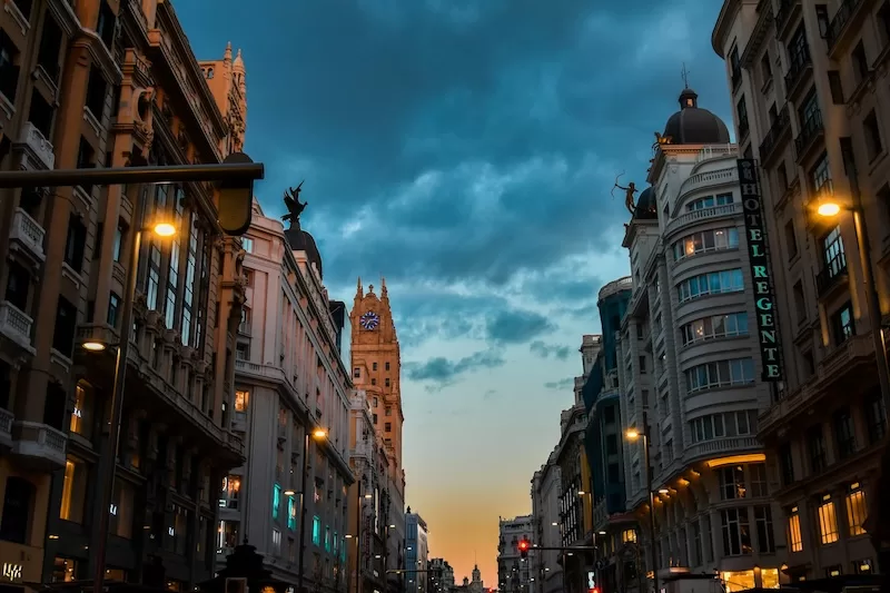 Evening settles over Gran Vía, Madrid’s heartbeat in motion, where ambition hums beneath the glow of old-world façades.