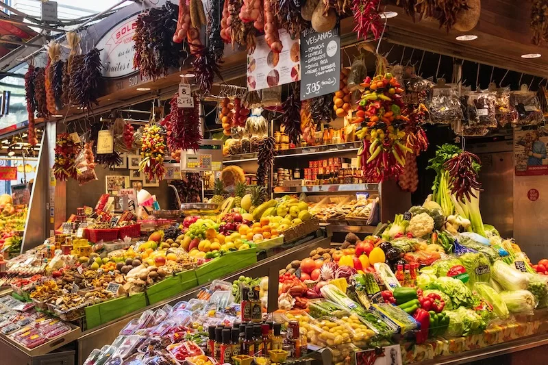 Colorful produce stalls at a local market in Spain. Shopping here can cut grocery costs and add a little Mediterranean flavor to your weekly routine.