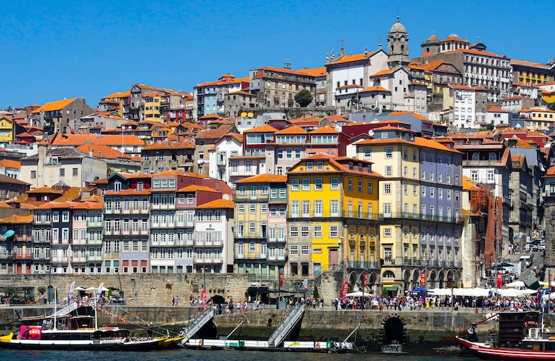 Ribeira district at its best: boats on the Douro, sunlight on azulejos, and daily life unfolding along the quay.