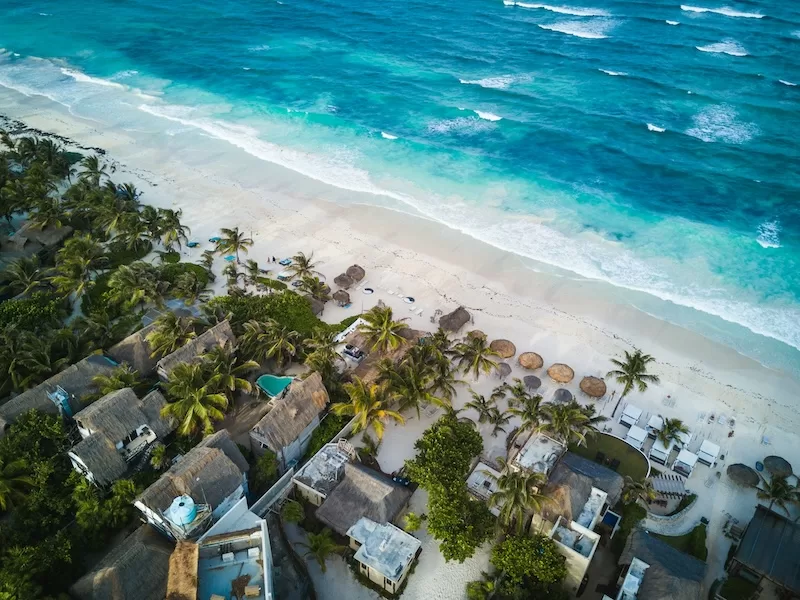 An aerial view of Tulum’s coastline, where turquoise water, white sand, and palm-thatched villas capture the essence of Mexico’s Caribbean lifestyle.