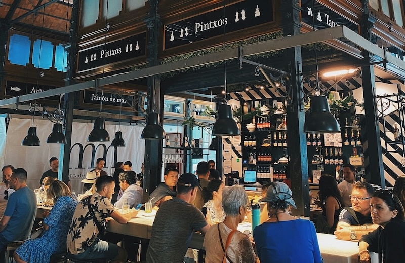Locals sharing pintxos at Madrid’s Mercado de San Miguel, proof that quality of life in Spain comes from connection, not consumption. Affordable social dining keeps community at the heart of everyday life.