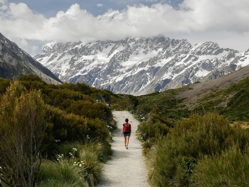 A lone hiker follows a trail toward Mount Cook, where New Zealand’s best weekends are free: fresh air, open paths, and no price tag.