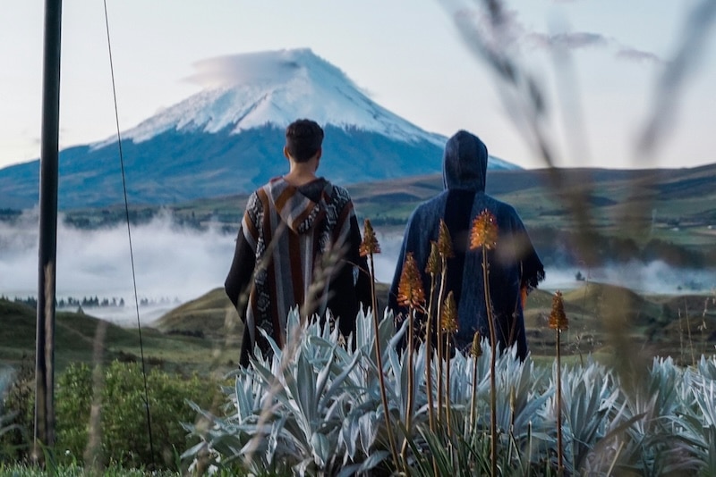 Two people stand before Cotopaxi Volcano, the same landscape that inspires Ecuador’s Tigua painters. In the highlands, art often begins with the earth: its colors, patterns, and rhythm mirrored in woven textiles and painted wood.