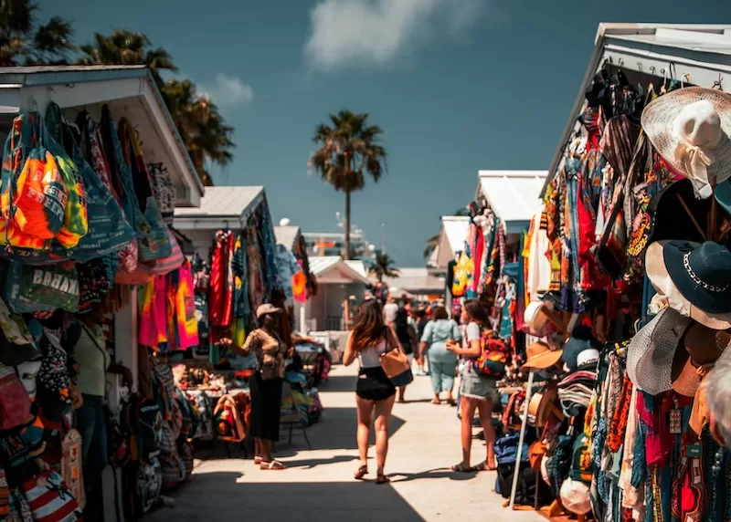 Market aisles brighten like a festival, fabrics swaying in the salt breeze as vendors chat through the lull of midday heat. Browsing turns social here. A quick errand can stretch into stories, a new bag, maybe a tip on where the best conch salad waits once the sun dips lower.