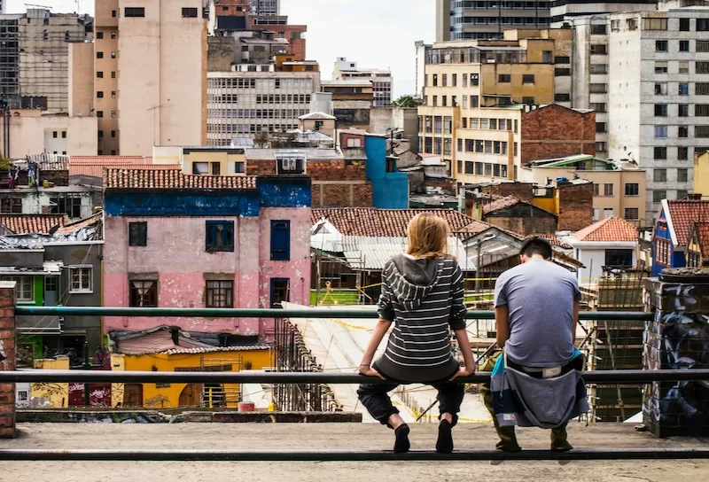 Two young people overlook the rooftops of Bogotá, where fast-paced city life reshapes how Colombian families live, work, and gather.