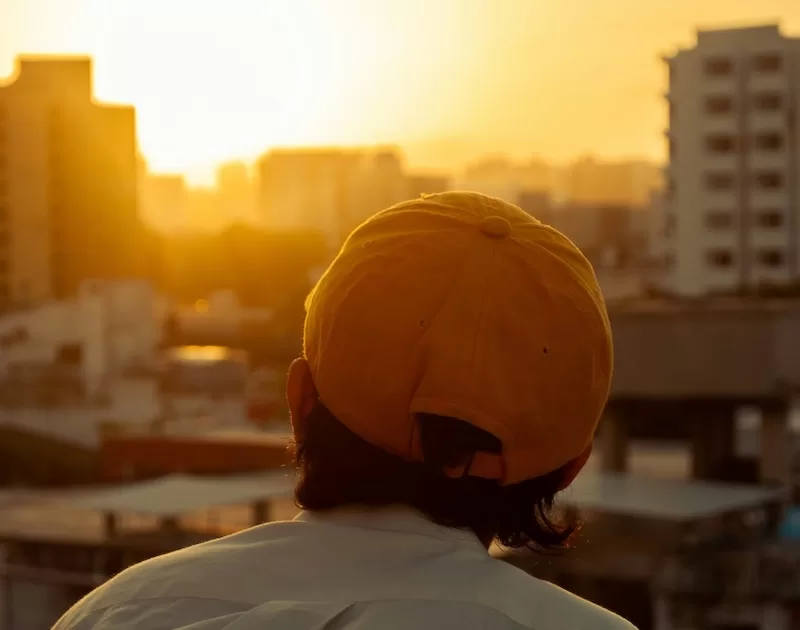 A young man watches the sunset over the city skyline, a symbol of Colombia’s next generation, navigating change while carrying forward the enduring values of family and connection.