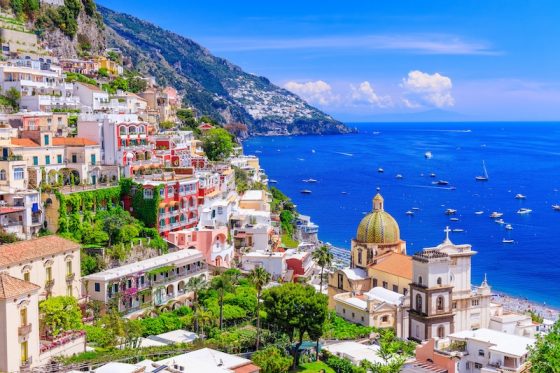 Colorful cliffside village of Positano Italy with pink and white buildings overlooking Mediterranean Sea showing Mediterranean charm for expats relocating