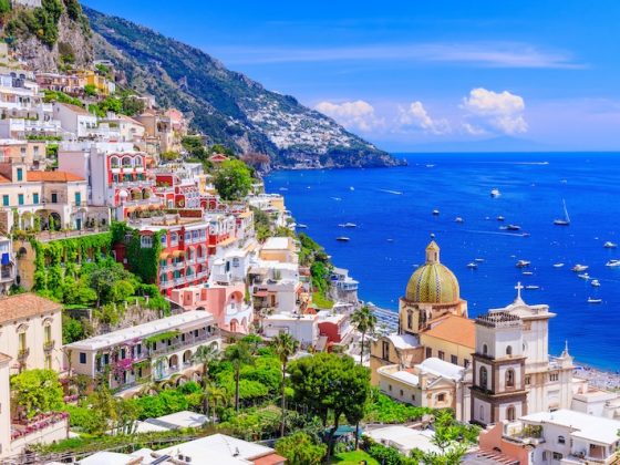 Colorful cliffside village of Positano Italy with pink and white buildings overlooking Mediterranean Sea showing Mediterranean charm for expats relocating