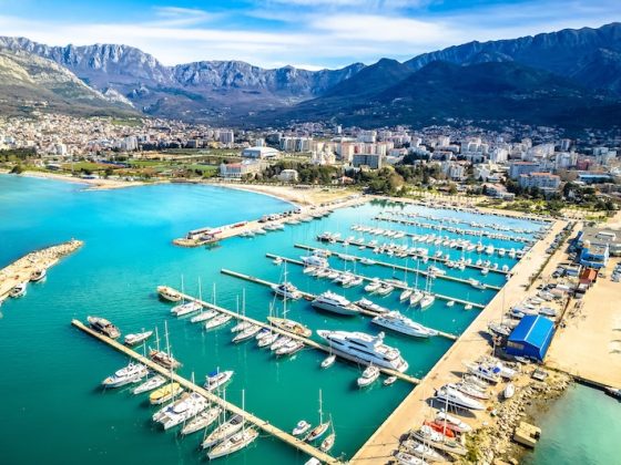 Aerial view of Montenegro's Adriatic harbor with yacht marina and mountain backdrop, representing Montenegro's appeal as a small country expat destination with European optionality